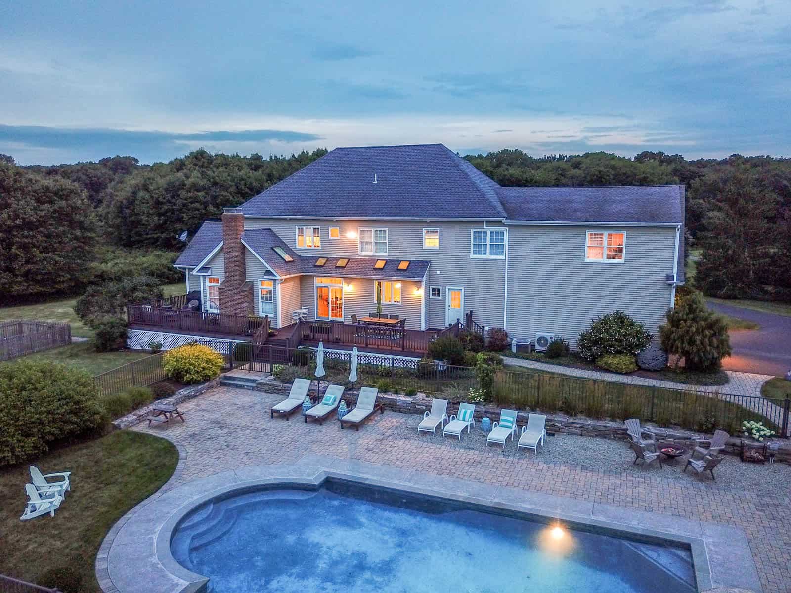 backyard of home with pool, chairs, and fire pit at dusk in Connecticut
