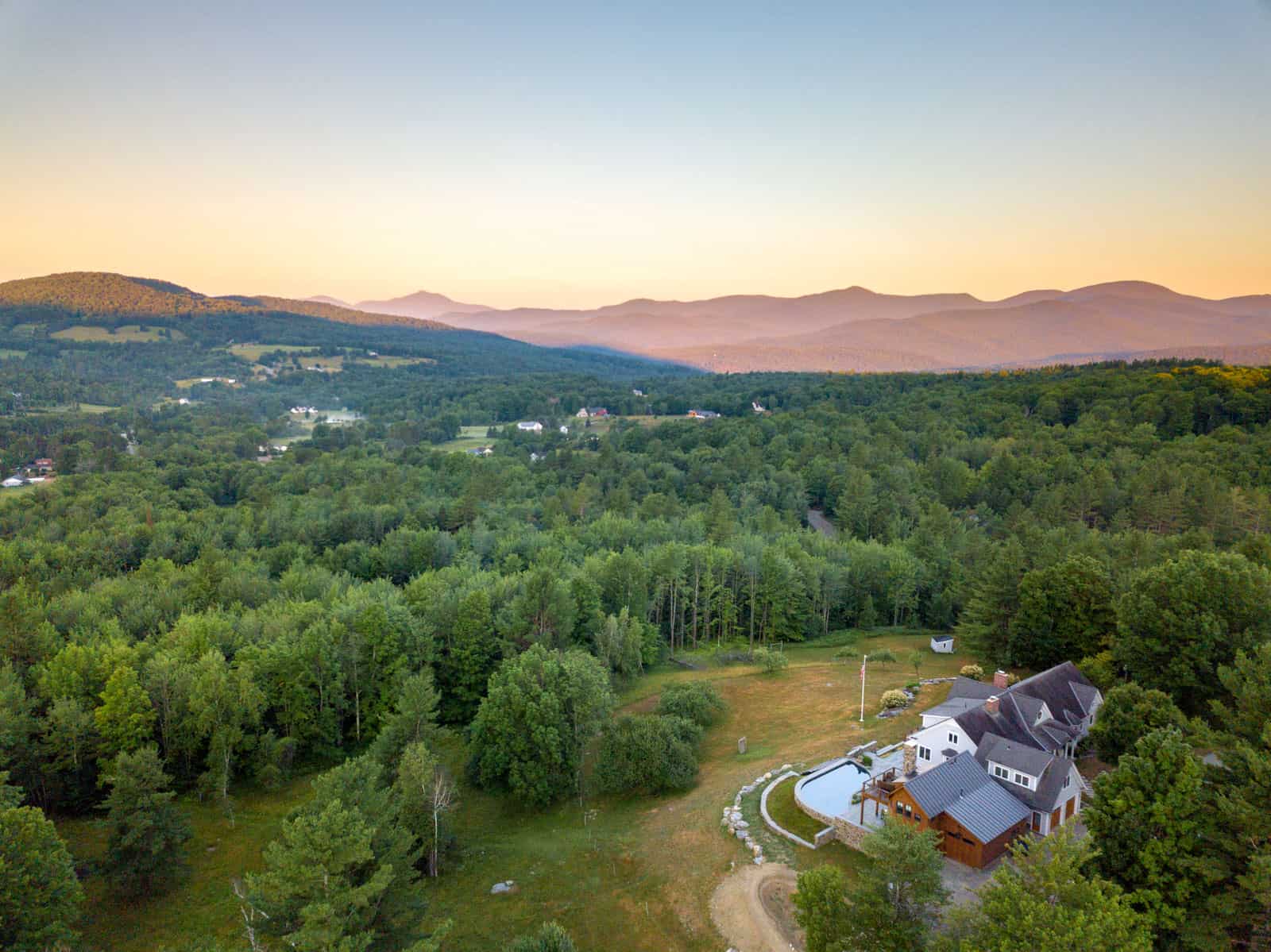 house in Stowe, VT aerial drone photo during sunrise with mountains in background