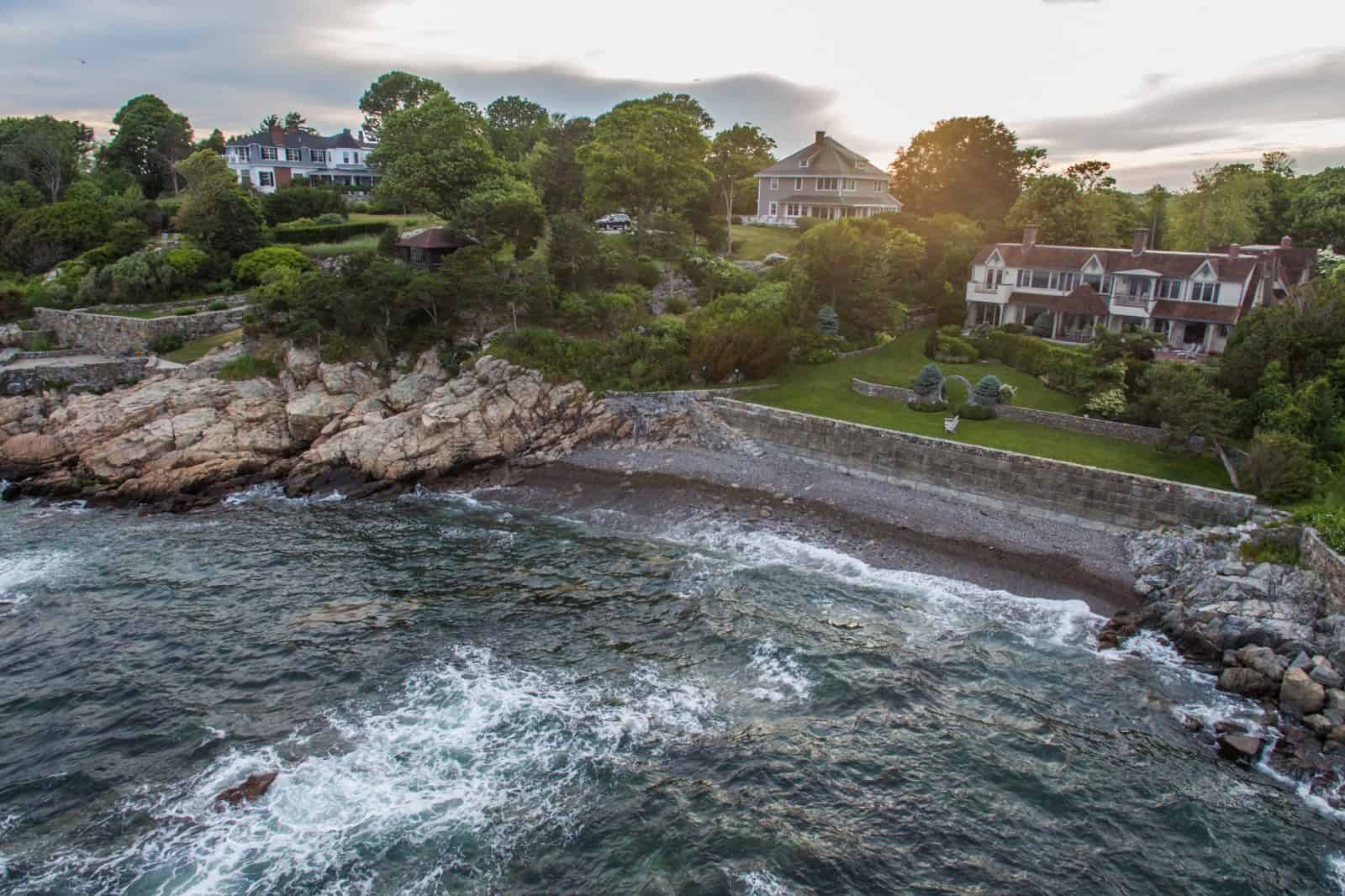 aerial drone photo of residential real estate property in Manchester-by-the-Sea, MA with ocean and sunset