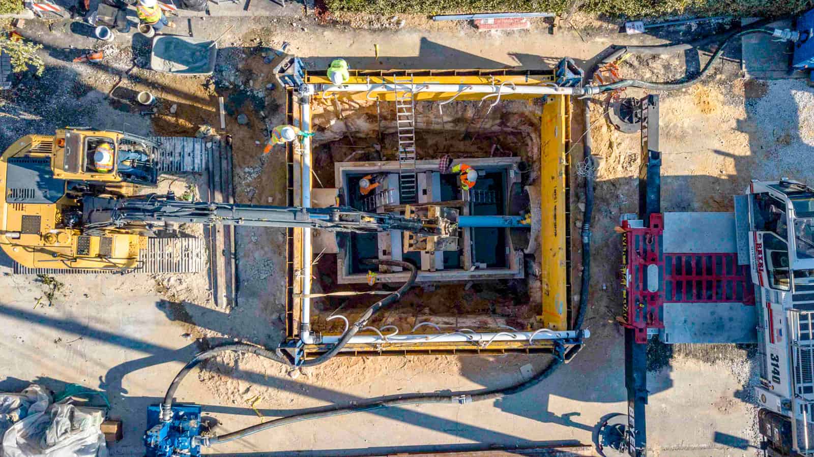aerial view looking down at construction site where 6 workers in yellow vests are installing a new water pipe in Florida