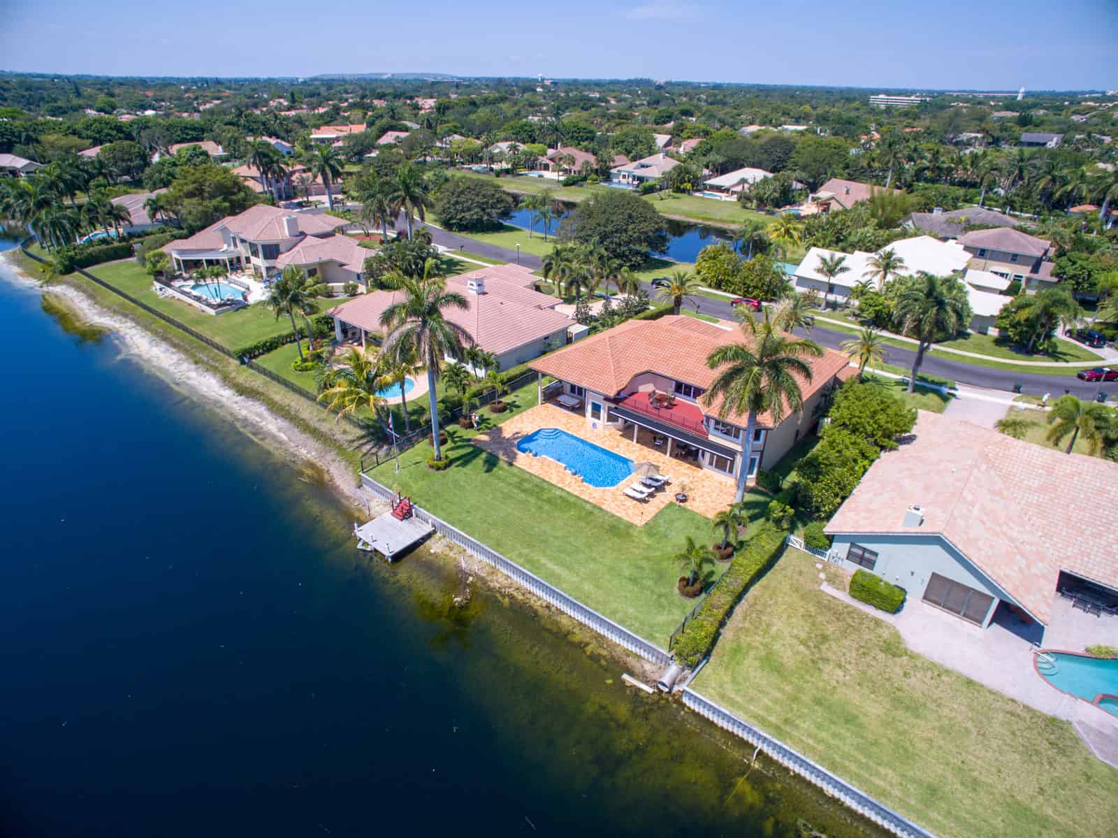home in Florida next to lake with swimming pool in backyard and palm trees